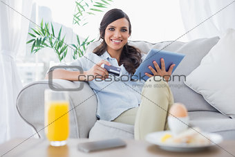 Peaceful brunette buying online while having breakfast