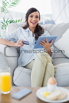 Cheerful gorgeous brunette buying online having breakfast