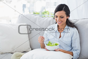 Woman relaxing on the sofa eating salad