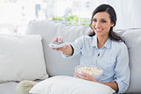 Pretty woman watching tv eating popcorn