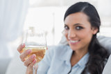 Attractive brunette offering white wine to camera