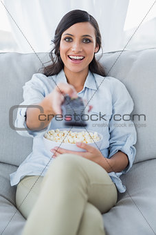 Happy pretty brunette watching tv and eating pop corn