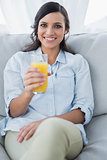 Smiling brunette offering orange juice to camera