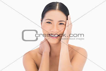 Smiling natural dark haired model touching her face