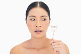 Apprehensive natural model holding eyelash curler