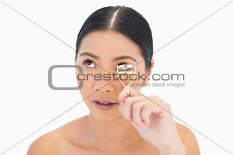 Natural model using eyelash curler looking up