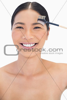 Cheerful pretty natural model using eyebrow brush