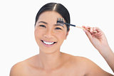 Smiling gorgeous natural model using eyebrow brush