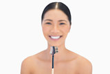 Smiling natural model holding eyebrow brush in front of her
