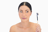Curious natural brunette holding eyebrow brush