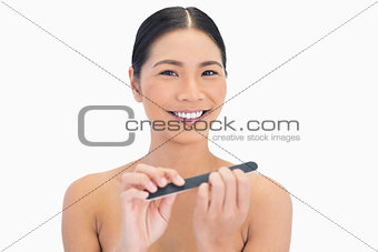 Cheerful natural brunette using nail file