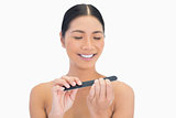 Happy natural brunette using nail file