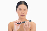 Frowning natural brunette using nail file