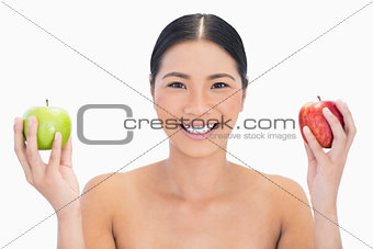 Cheerful black haired model holding apples in both hands
