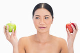 Black haired model holding apples in both hands looking at the green one