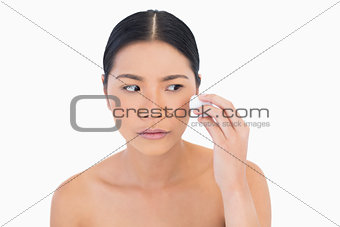 Curious beautiful model using cotton pad on her face