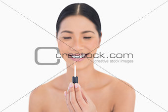Happy beautiful model holding lip gloss in front of her