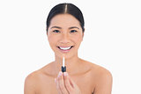 Smiling attractive model holding lip gloss