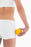 Toned female buttocks with orange on hand