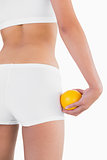 Toned female buttocks with orange on hand