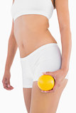 Slender female body with white sport underwear holding orange