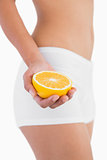 Toned female body holding half orange