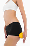 Female slender body with sport underwear holding orange