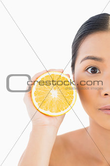 Half face of surprised pretty woman with orange