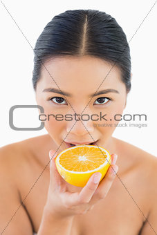 Pretty woman biting orange slice