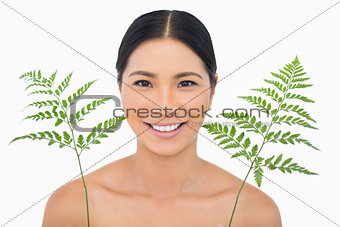 Cheerful sensual dark haired model posing with fern