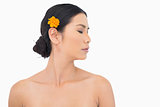 Pensive dark haired model with orange flower in hair