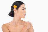 Pensive model with orange flower in hair touching her shoulder