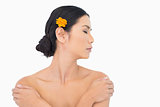Pensive model with orange flower in hair touching her shoulders