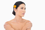 Thoughtful model with orange flower in hair touching her shoulders