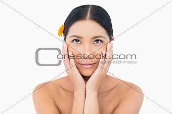 Dreaming sensual model with orange flower in hair touching her face