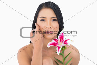 Natural black haired model posing with lily and caressing her face