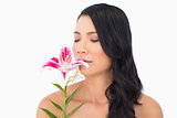 Natural brown haired model smelling lily closing eyes