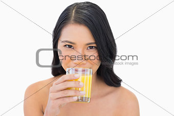 Sensual nude model drinking orange juice