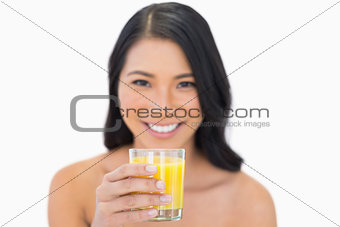 Smiling sensual nude model drinking orange juice
