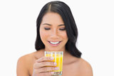 Cheerful sensual nude model drinking orange juice