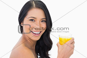 Cheerful sensual nude model with glass of orange juice