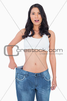 Surprised sexy woman wearing too big jeans