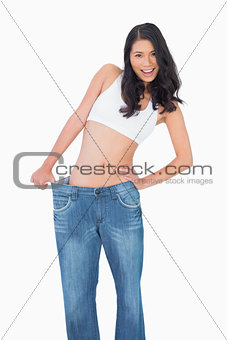 Smiling sexy woman wearing too big jeans