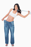 Woman wearing too big pants and strangling herself with measuring tape