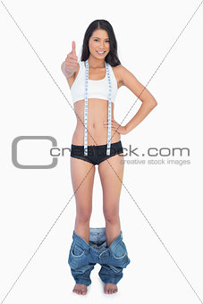 Sexy woman with too big pants on her ankles thumbs up