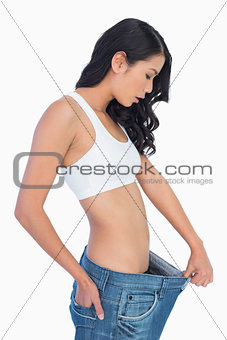 Surprised woman holding her too big jeans