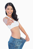 Victorious woman holding her too big pants and pointing out at camera