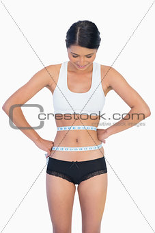 Smiling slim woman measuring her waist