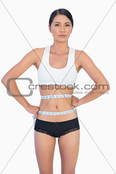 Self confident slim woman measuring her waist