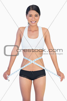 Cheerful slim woman measuring her waist